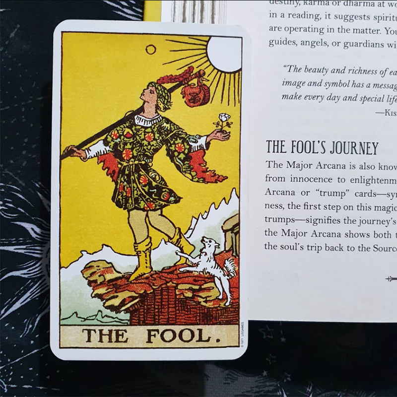 The Fool card from the Original Rider Waite Smith tarot, placed on top of a page of The Modern Witch's Book of Tarot by Skye Alexander