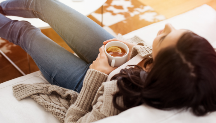 woman taking break on a couch holding a cup of tea